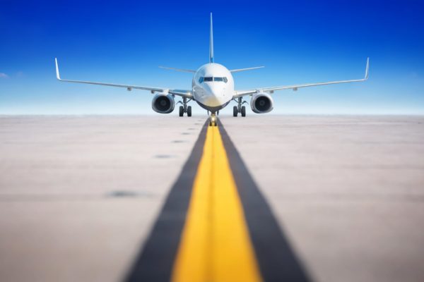 Front shot of an aircraft with a yellow line taxiway and blue sky